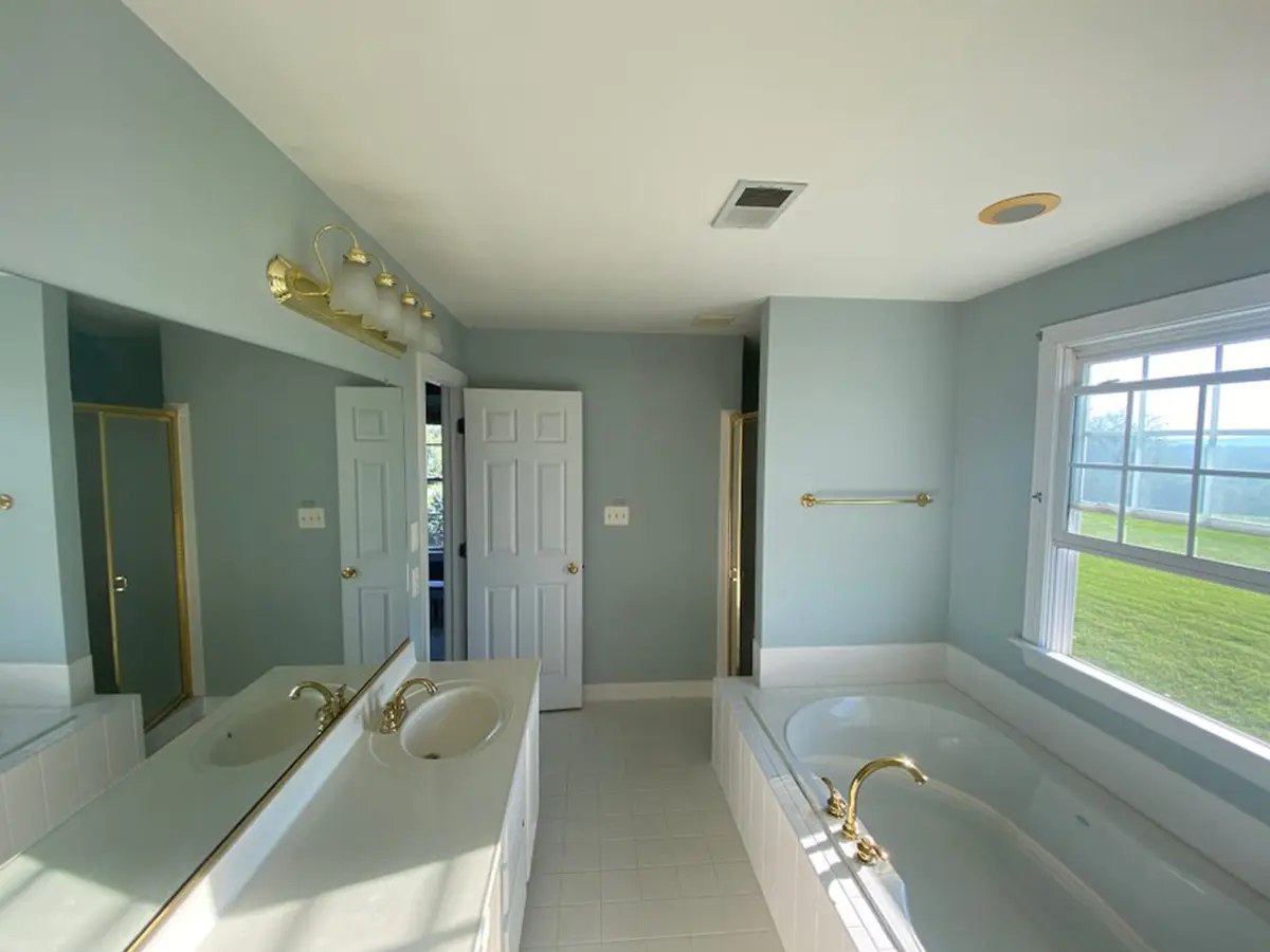 Older blue bathroom with golden fixtures prior to bathroom remodel from MGS Contracting Services