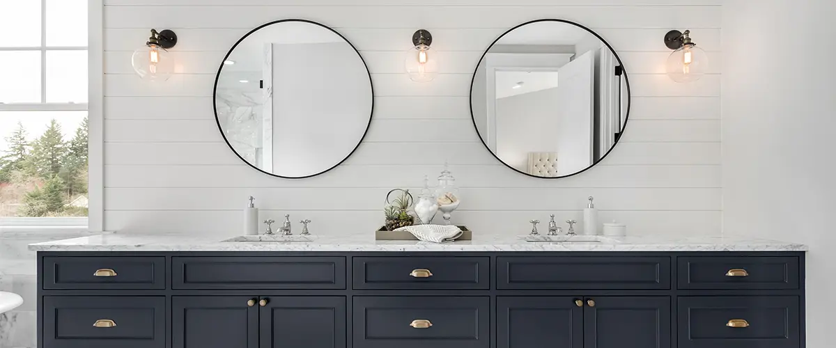 A bathroom remodeling in Leesburg VA with a double vanity painted dark blue and two round mirrors