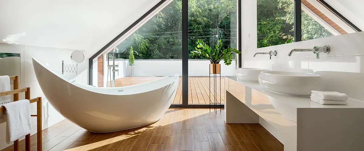 A free standing tub in a bathroom with large windows and a beautiful view outside
