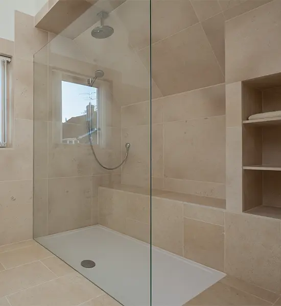 A glass walk-in shower with a shower pan and no door