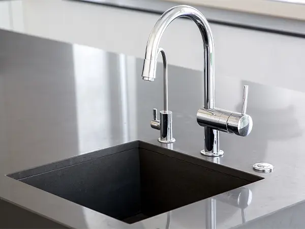 A silver faucet on a dark countertop