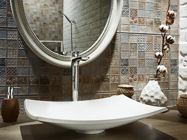 A vessel sink with a round mirror and a beautiful backsplash