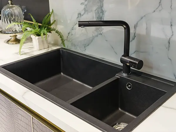 A black sink with a dark faucet