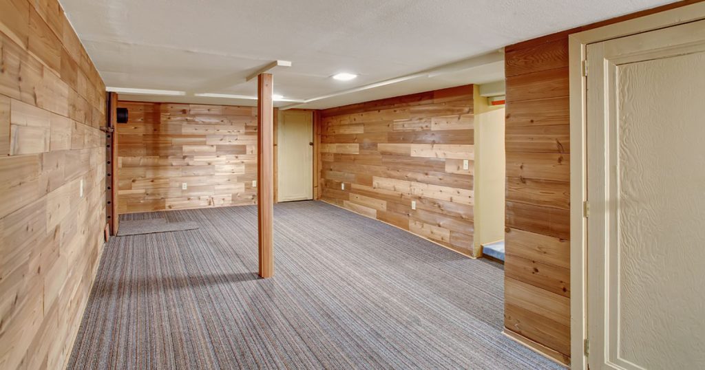 An empty finished basement with what looks like wood on walls