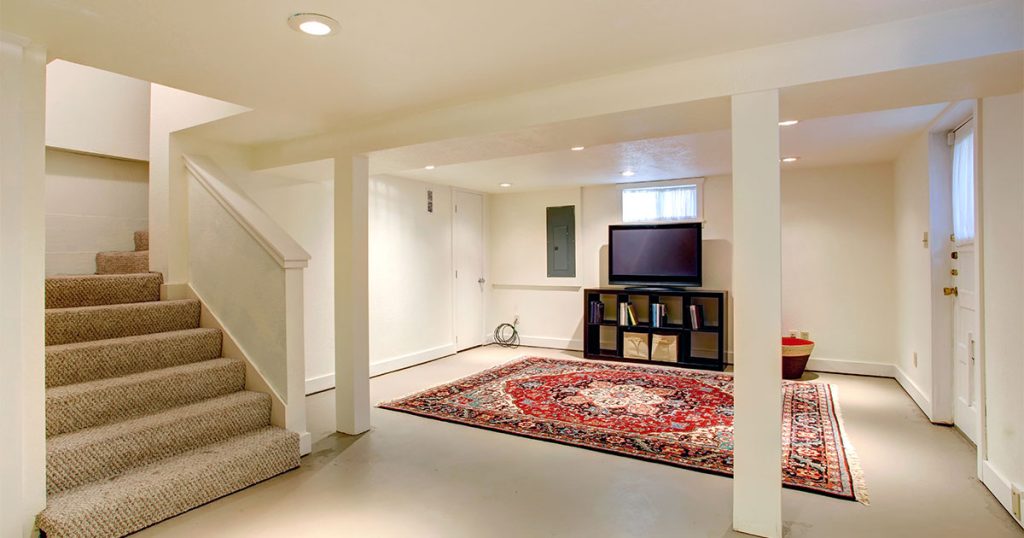 A large basement transformed into a living space with a red carpet and a large TV