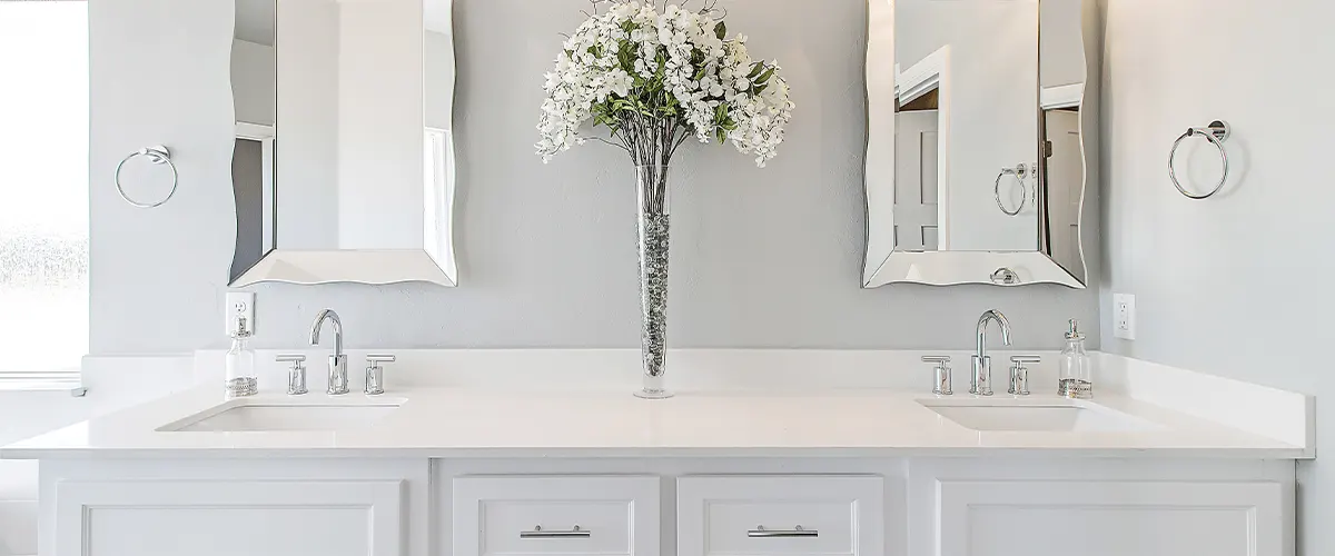 white sleek bath with a vase of flowers on the white countertop