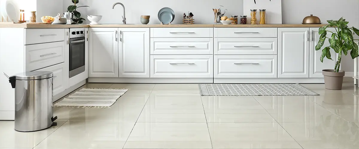 A tile kitchen flooring with white cabinets