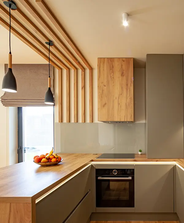A kitchen with modern beige cabinets, pendant lights, and wood features