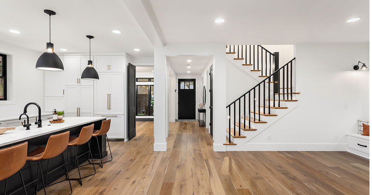 An open concept kitchen with wood flooring, white cabinets, and wood stools