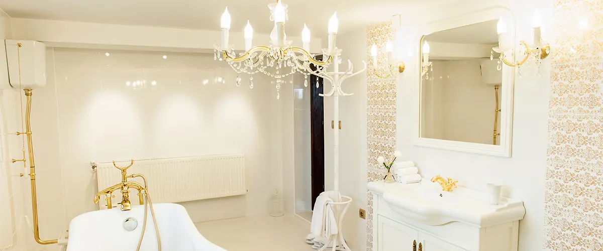 A chandelier in a bathroom with white and gold colors