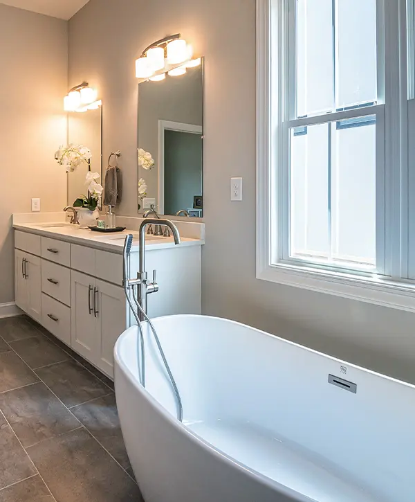 Freestanding tub with white vanity and tile flooring