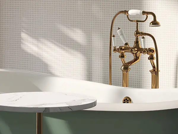 A tub with golden water fixture and a small quartz table