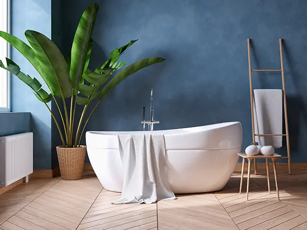 A freestanding tub in a bathroom with wood floor and blue walls
