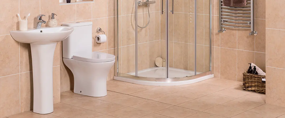 A pedestal sink in a bathroom with a framed shower and a toilet