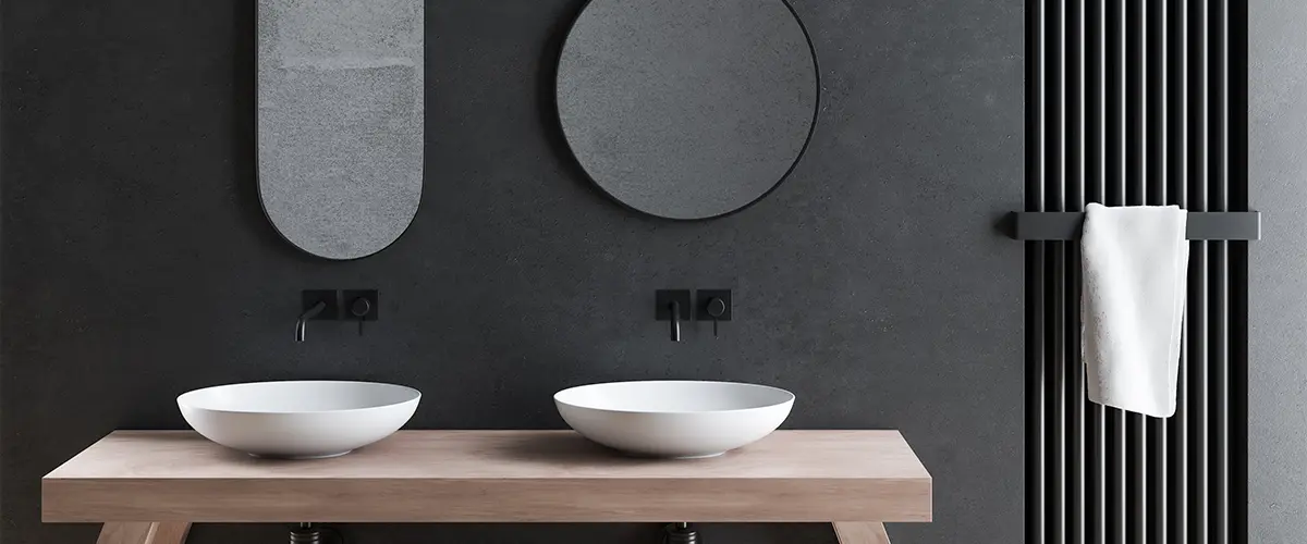 Two vessel sink in a black bathroom with two different shaped mirrors