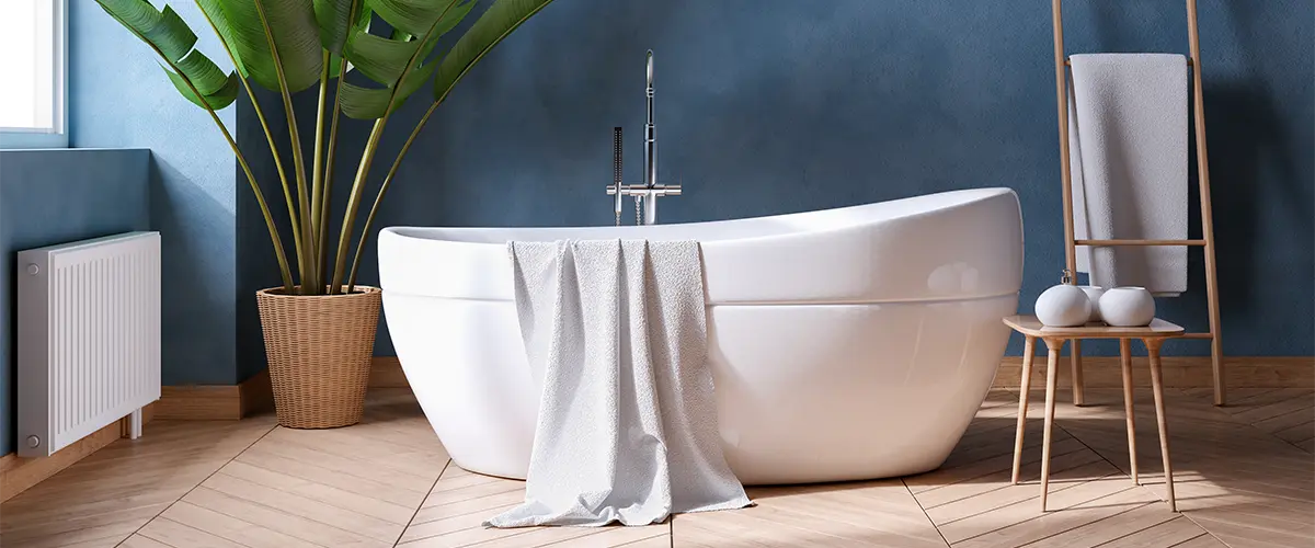 A beautiful freestanding tub and wood flooring in a bath with walls painted blue
