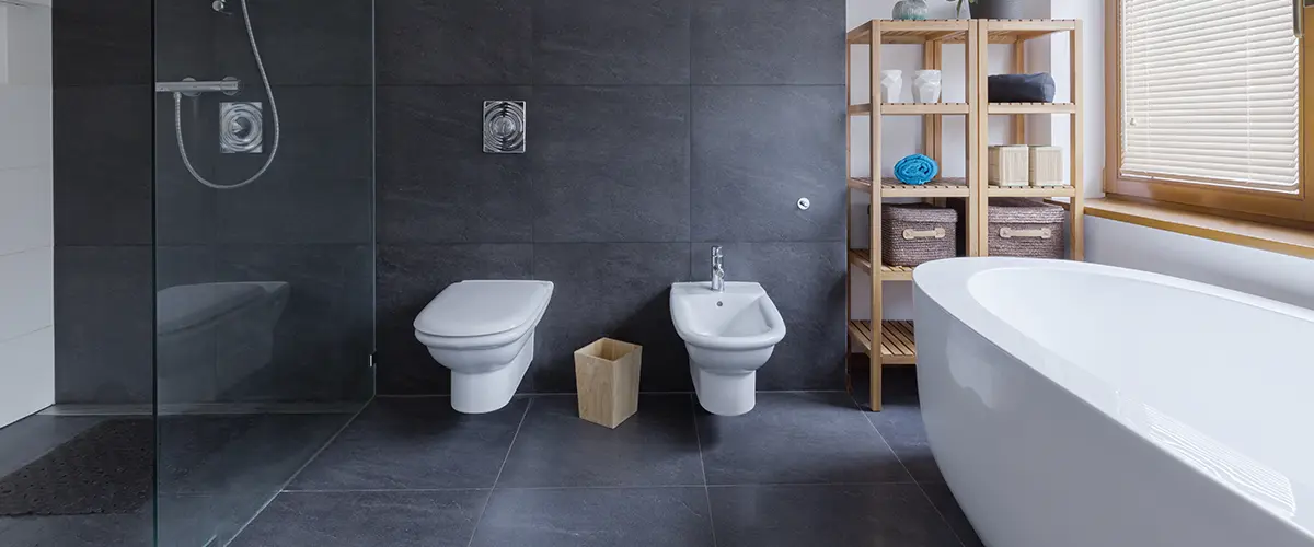 A modern bathroom with black large tile on the floor and walls