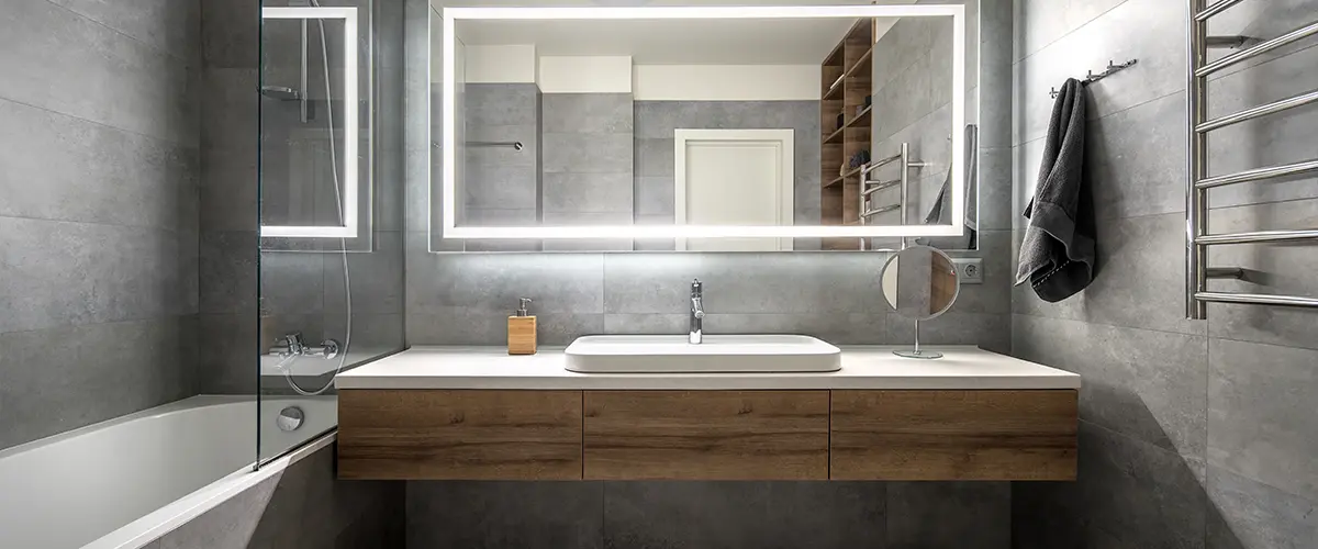 A modern wood vanity with a large rectangular mirror